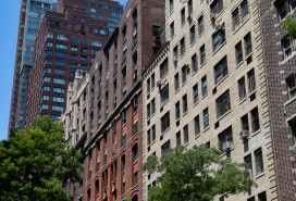A row of old brick apartment building skyscrapers along a street on the Upper West Side of New York City