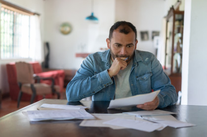 A man looks over several documents and looks concerned.