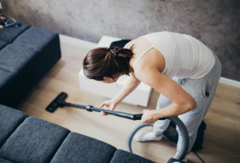 woman vacuuming the floor next to her couch