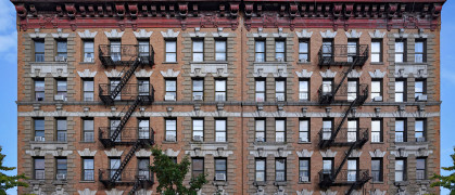 Old fashioned New York City apartment building with decorative roof cornice and external fire escapes