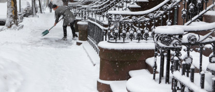 Brooklyn brownstone resident clears snow off sidewalk in winter