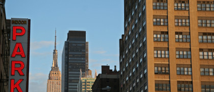 A photo of NYC buildings and a parking garage sign on the left