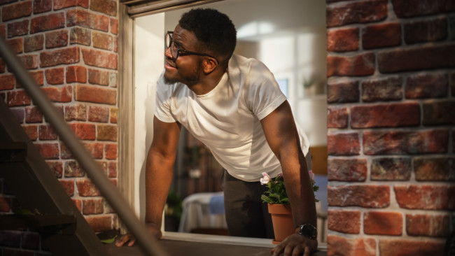 Man opening window in brick apartment building