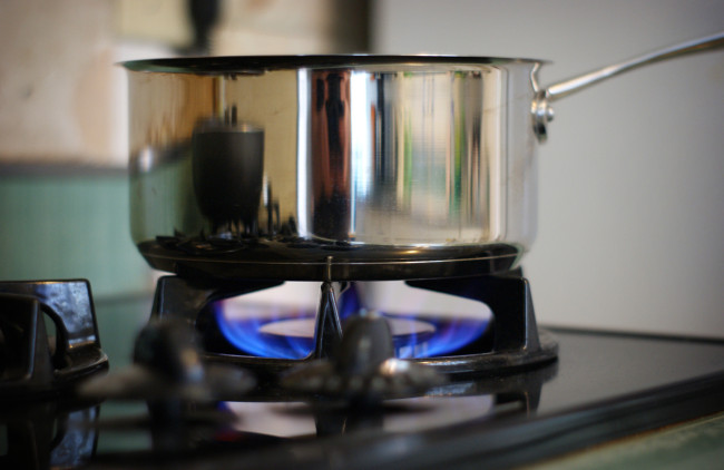 stainless steel saucepan being used on a gas cooktop