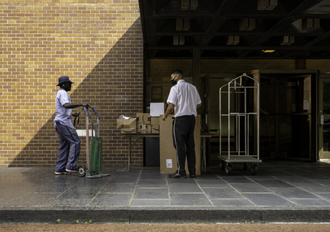 Postman transferring packages to the doorman of a residential building on Madison Avenue