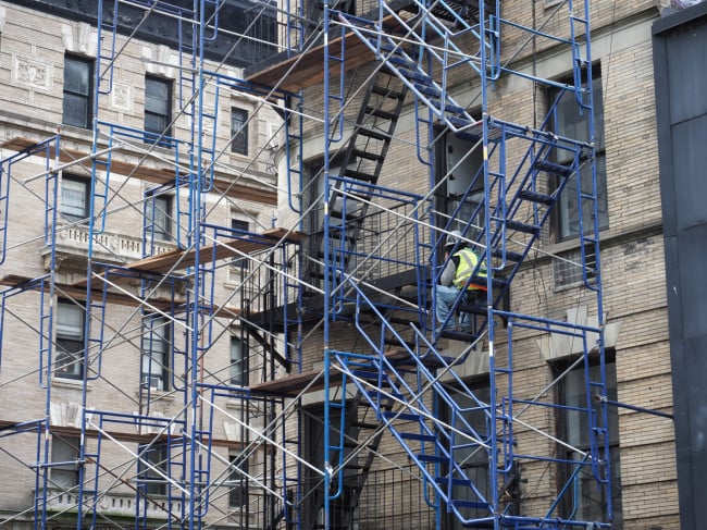 New York, USA - June 21, 2019: Image of a construction worker resting on a scaffold.