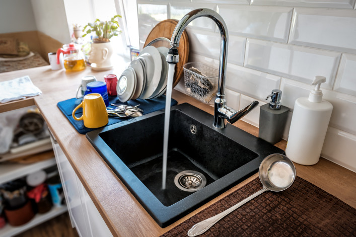 Water flowing out of a kitchen stainless steel tap into the sink.