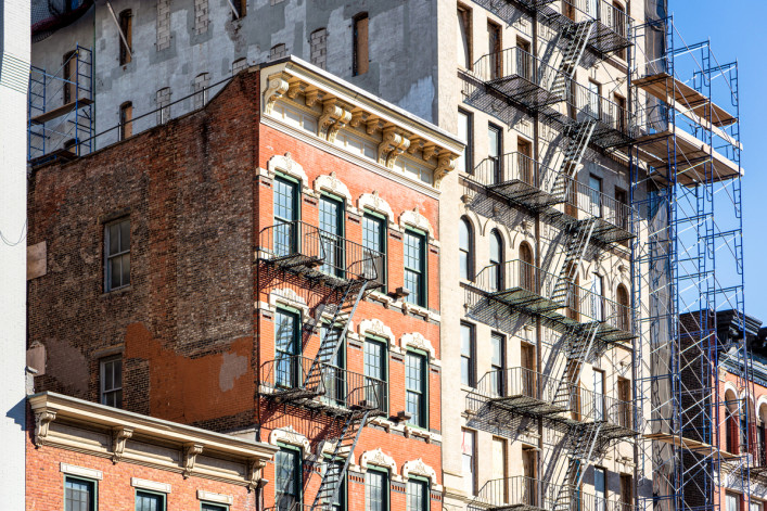 Traditional apartment buildings in New York City, circa 2019, building with scaffolding outside of it.