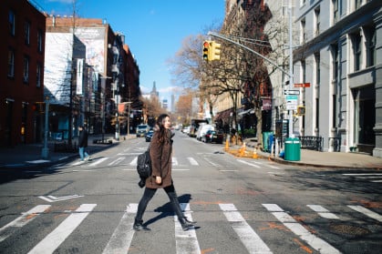 Young woman crossing the street in Manhattan, New York - stock photo