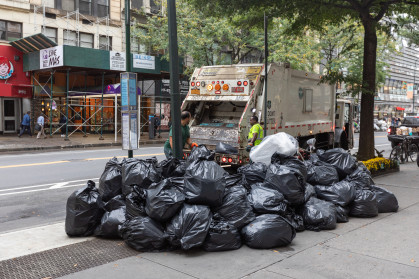 DSNY truck takes away black trash bags on an NYC street