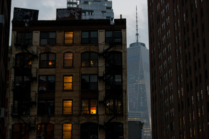 An apartment building and the World Trade Center One building in the background at twilight in Lower Manhattan.