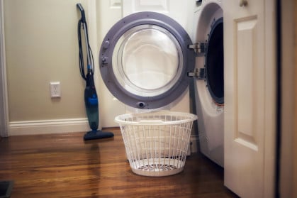 A laundry basket sitting next to an open washing machine