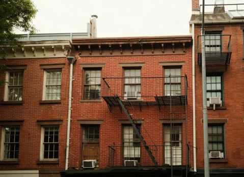 Classic pre-war style brick apartment buildings stand closely together, showing the density of new york city