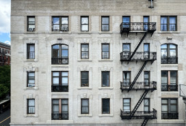 Front view of white pre-war apartment building facade seen from elevated subway station in Morningside Heights, Manhattan, New York City