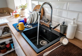 Water flowing out of a kitchen stainless steel tap into the sink.