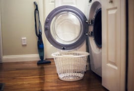 A laundry basket sitting next to an open washing machine