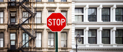 A photo of a stop sign in front of an NYC apartment building.