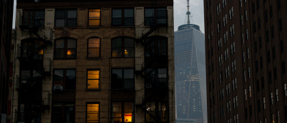 An apartment building and the World Trade Center One building in the background at twilight in Lower Manhattan.