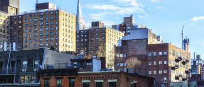 A street view of apartment buildings with the Empire State Building in the background at the High Line