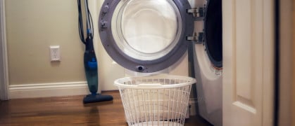 A laundry basket sitting next to an open washing machine