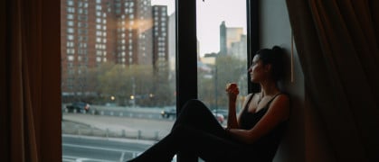 Young woman having an apple, relaxing by the window, enjoying the view in Manhattan, New York.