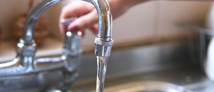 faucet with hand of woman in kitchen for cleaning, drinking and washing dishes. Interior, steel and household plumbing with sink and tap at home for stream, flowing and splash